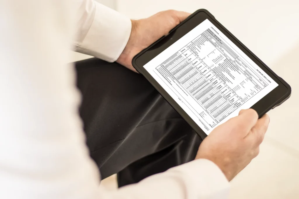 Person mit Tablet, das eine detaillierte Tabelle zur Heizlastberechnung anzeigt.