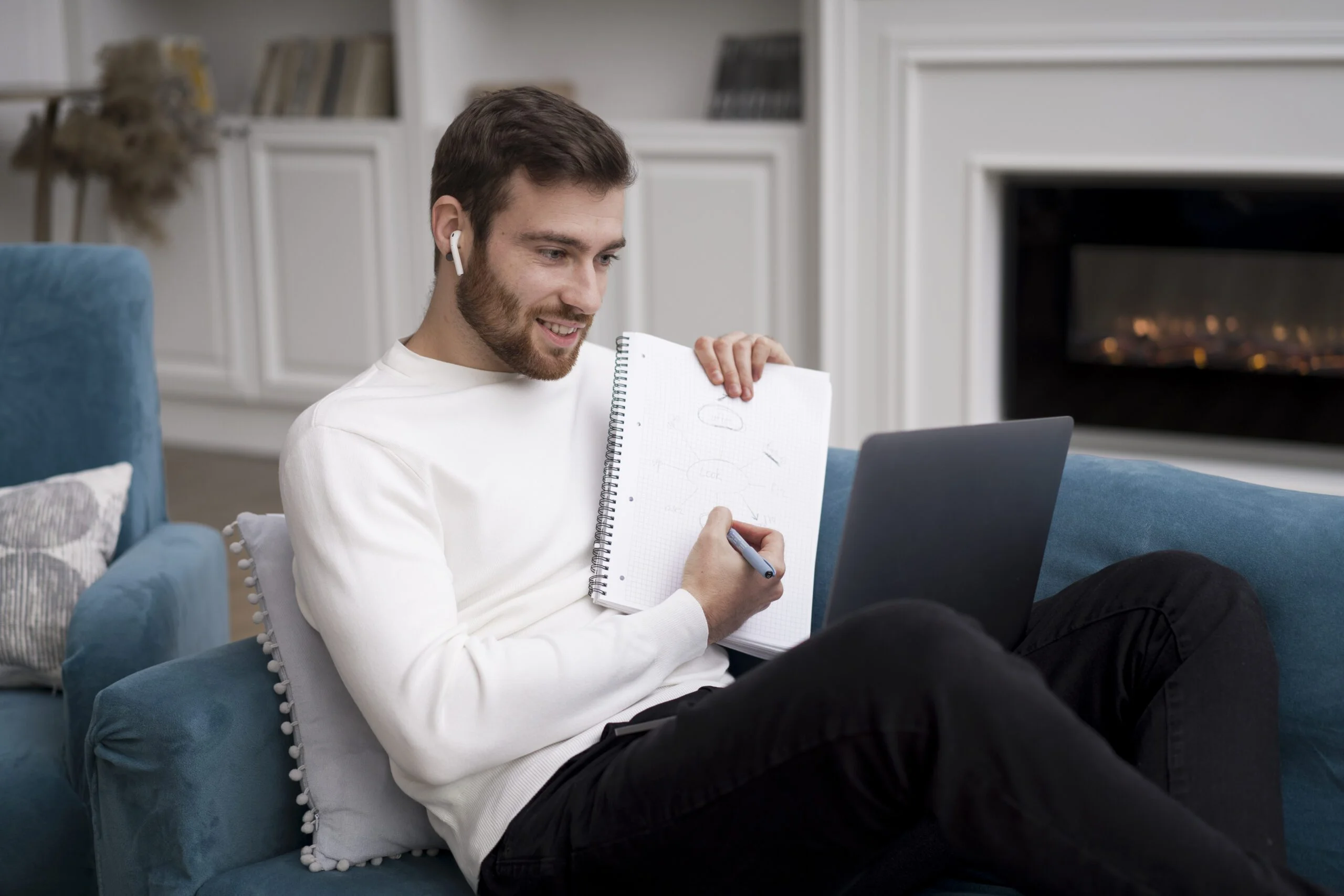 Mann mit Kopfhörern hält ein Notizbuch und gibt eine positive Rezension zur Heizlastberechnung online vor einem Laptop ab.